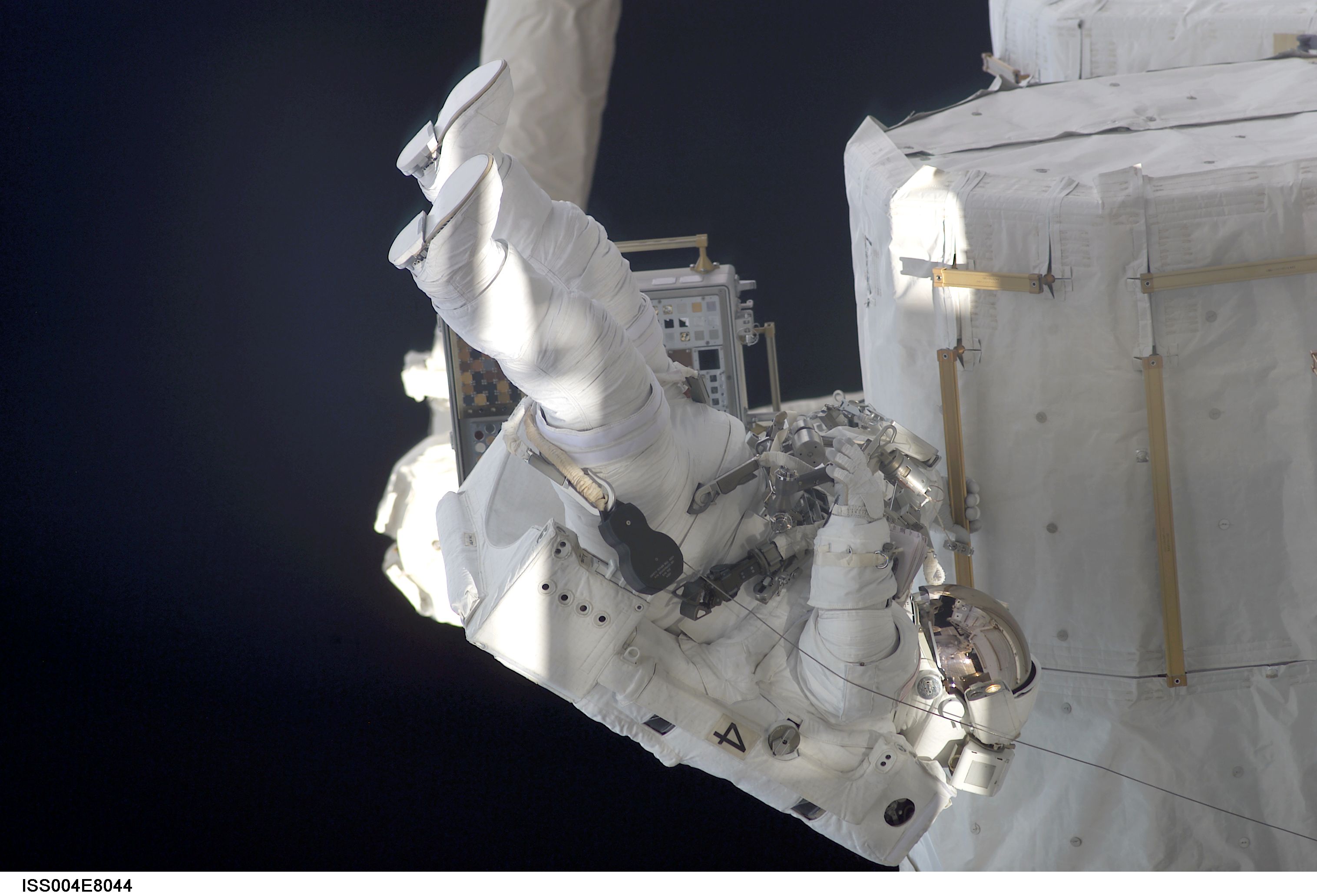 ISS004-E-8044 (20 February 2002) --- Astronaut Daniel W. Bursch, Expedition Four flight engineer, participates in the five-hour, 47-minute space walk on February 20, 2002. He moves near the oxygen and nitrogen tanks on the exterior of Quest Airlock. The square device (partially obscured by Bursch) on the Space Station Remote Manipulator System (SSRMS) or Canadarm2 is the Materials International Space Station Experiment (MISSE). The image was recorded with a digital still camera.