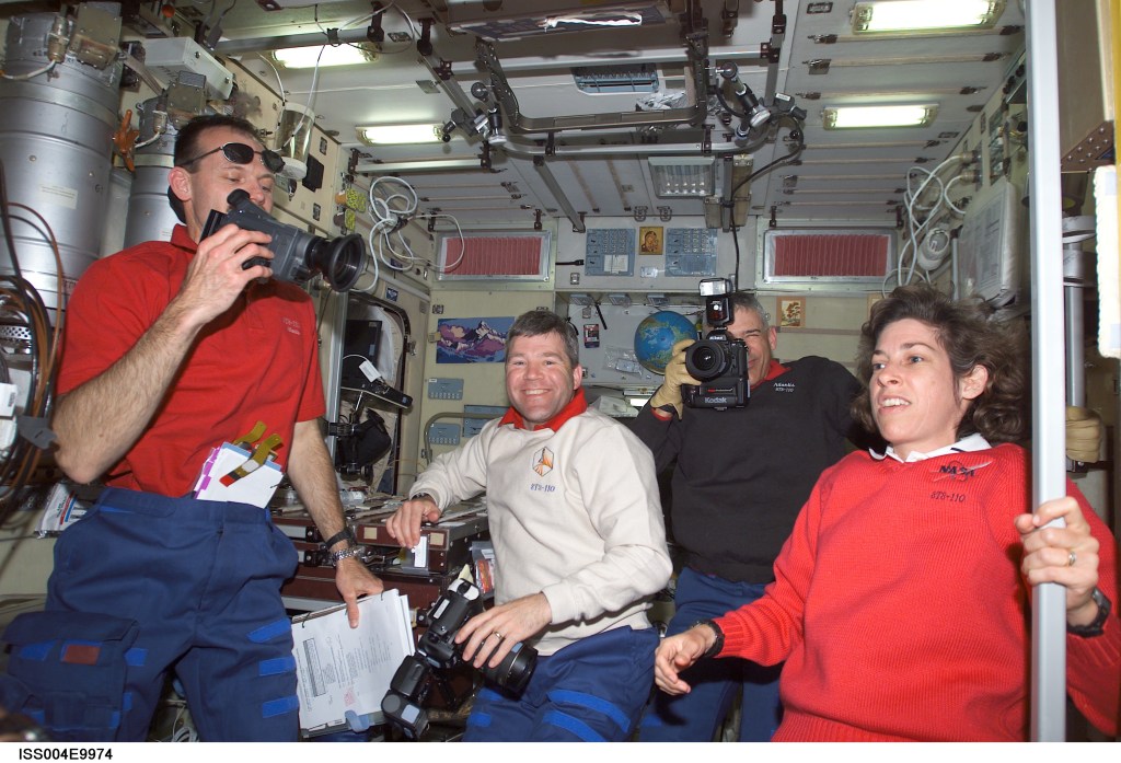 ISS004-E-9974 (10 April 2002) --- Astronauts Steven L. Smith (left), STS-110 mission specialist, Stephen N. Frick, pilot, Lee M. E. Morin, mission specialist, hold cameras in the Zvezda Service Module on the International Space Station (ISS) while astronaut Ellen Ochoa, mission specialist, looks on.