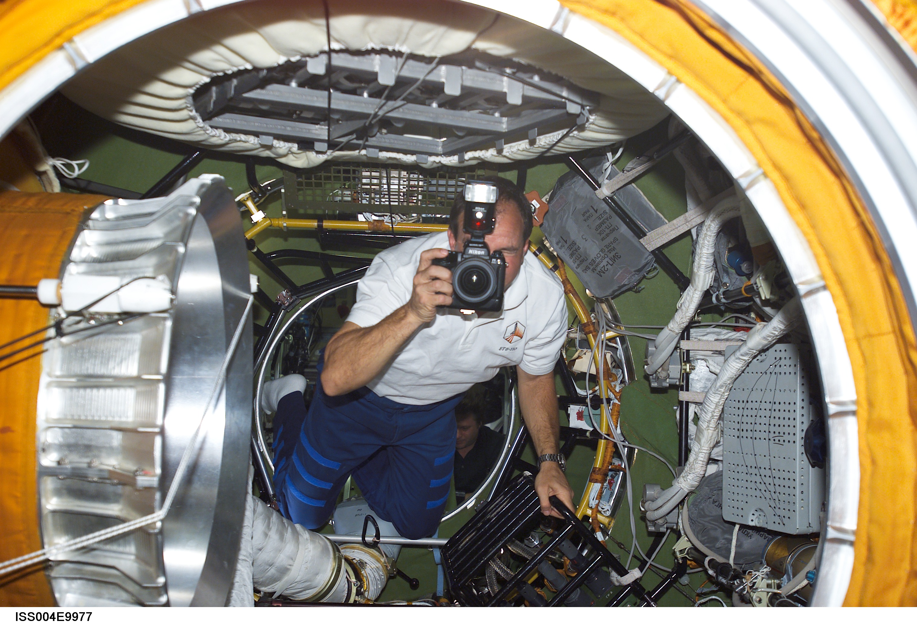 ISS004-E-9977 (10 April 2002) --- Astronaut Michael J. Bloomfield, STS-110 mission commander, uses a still camera in the Zvezda Service Module’s transfer compartment on the International Space Station (ISS).