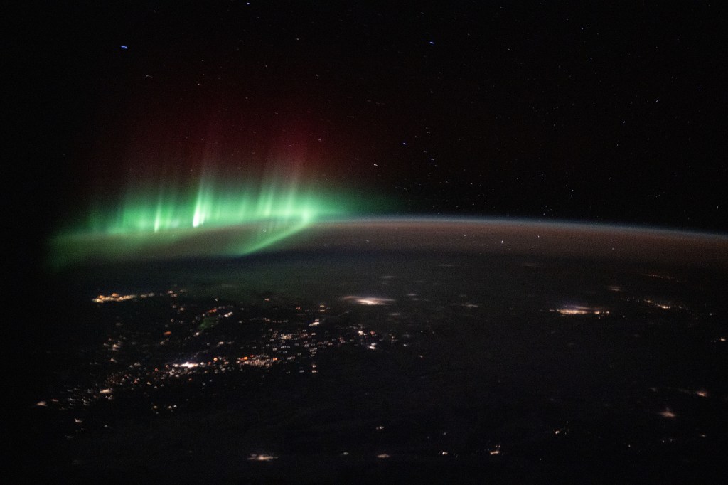 iss072e159772 (Nov. 10, 2024) -- As the International Space Station orbited 259 miles above Earth, right off coast of Vancouver, NASA astronaut Don Pettit captured this image of city lights and a green aurora dancing in the atmosphere above.
