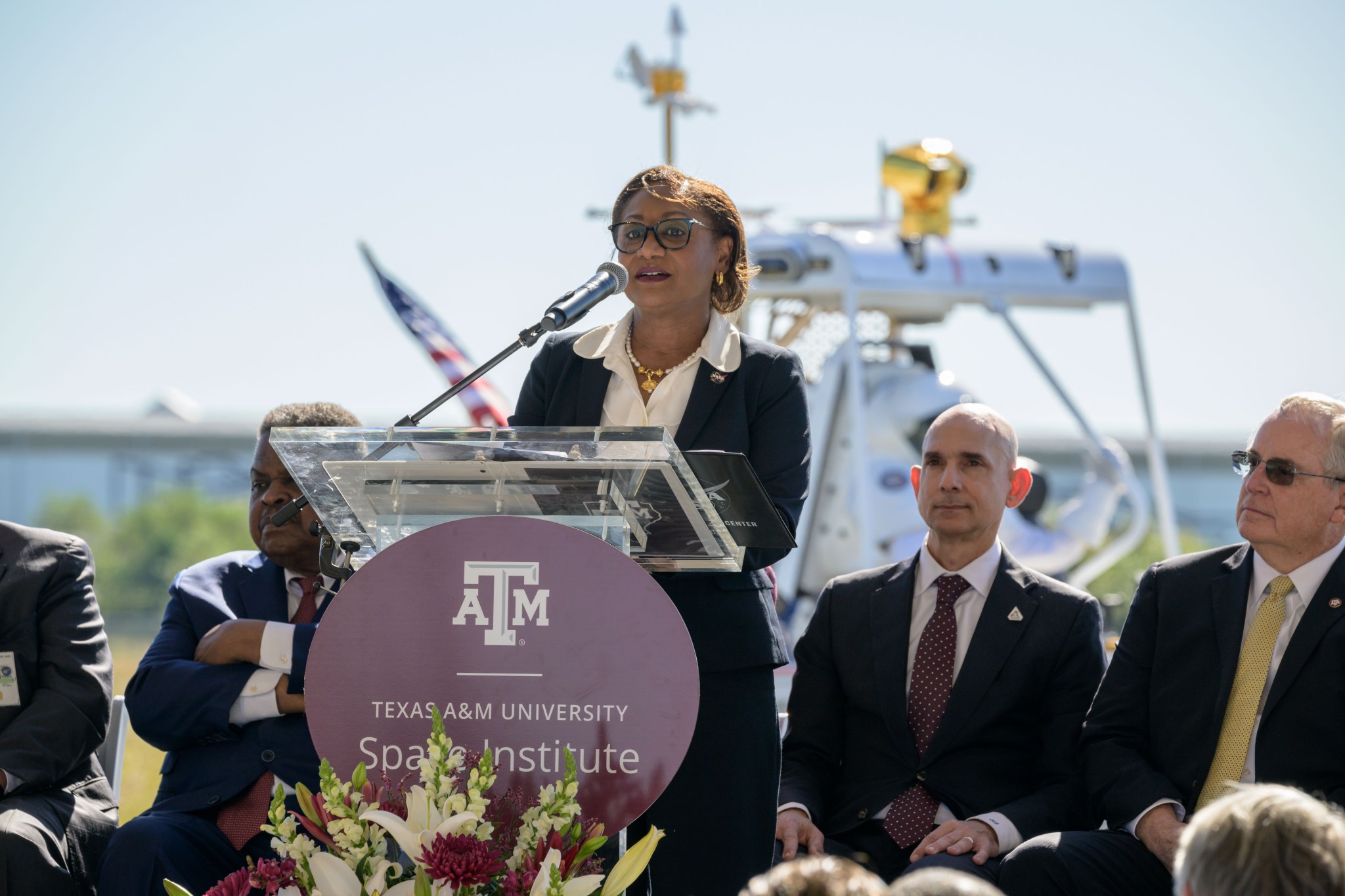 Speaker at the podium during the Texas A&M University Space Institute event, surrounded by panelists.