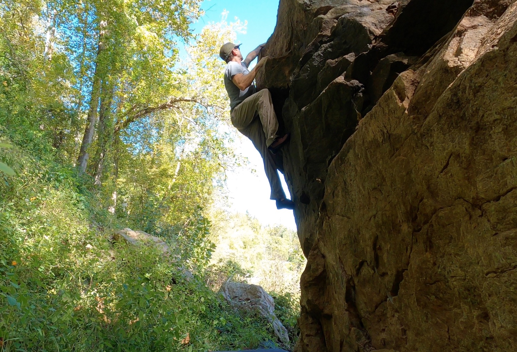 A man clings to the side of a cliff.