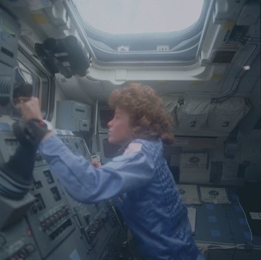 experimental flight model Anna L. Fisher operates the Remote Manipulator System from Discovery’s aft flight deck