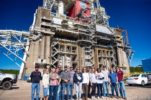 a group of college students pose for a photo in front of the Thad Cochran Test Stand while touring key facilities at NASA Stennis