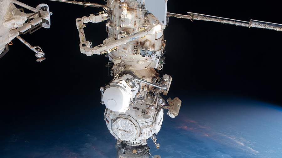 Two cosmonauts work outside the space station to activate a radiator on the Nauka science module during a spacewalk on May 12, 2023. At top, is the European robotic arm attached to Nauka.