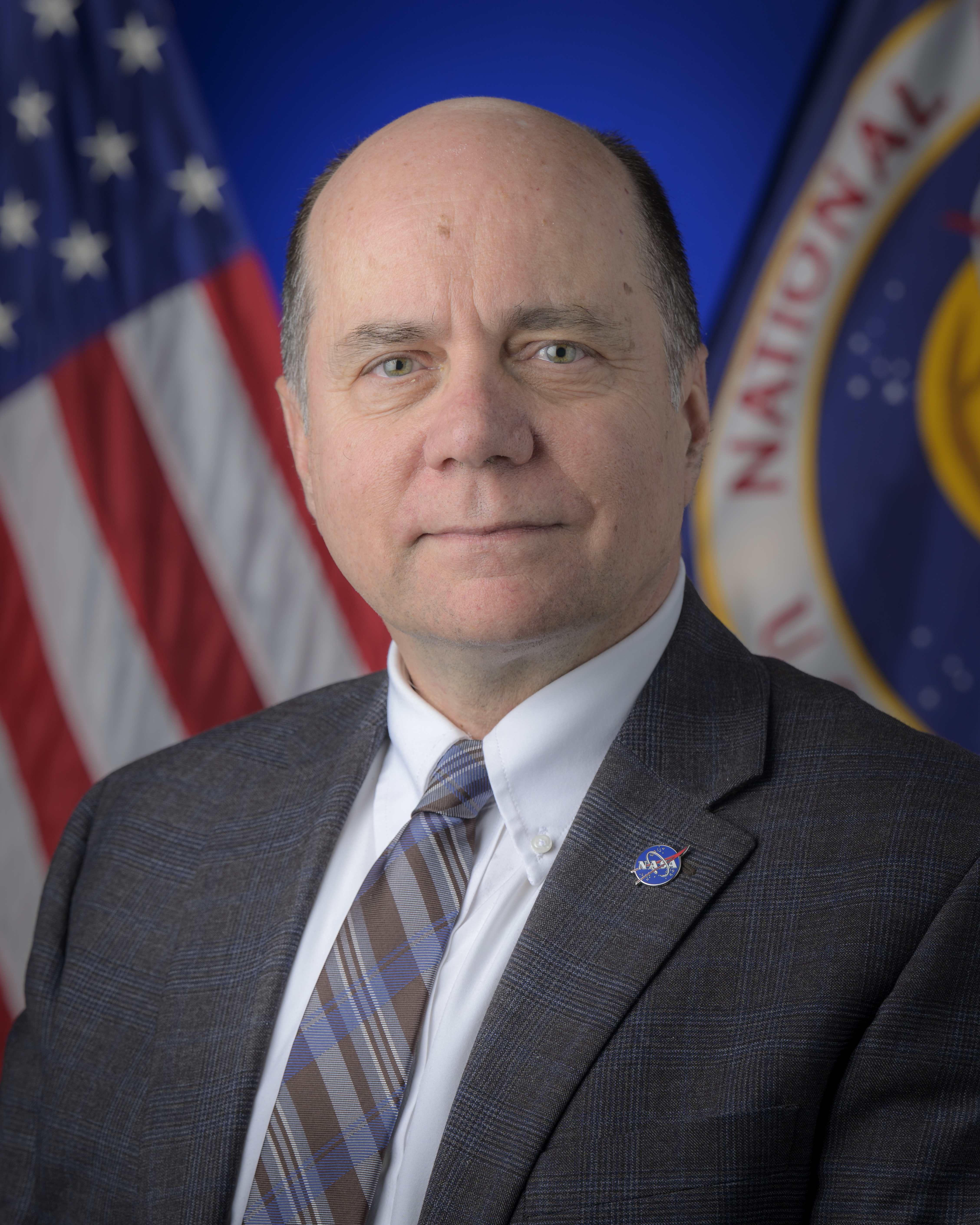 Official portrait of David Mitchell with American and NASA flag in the background