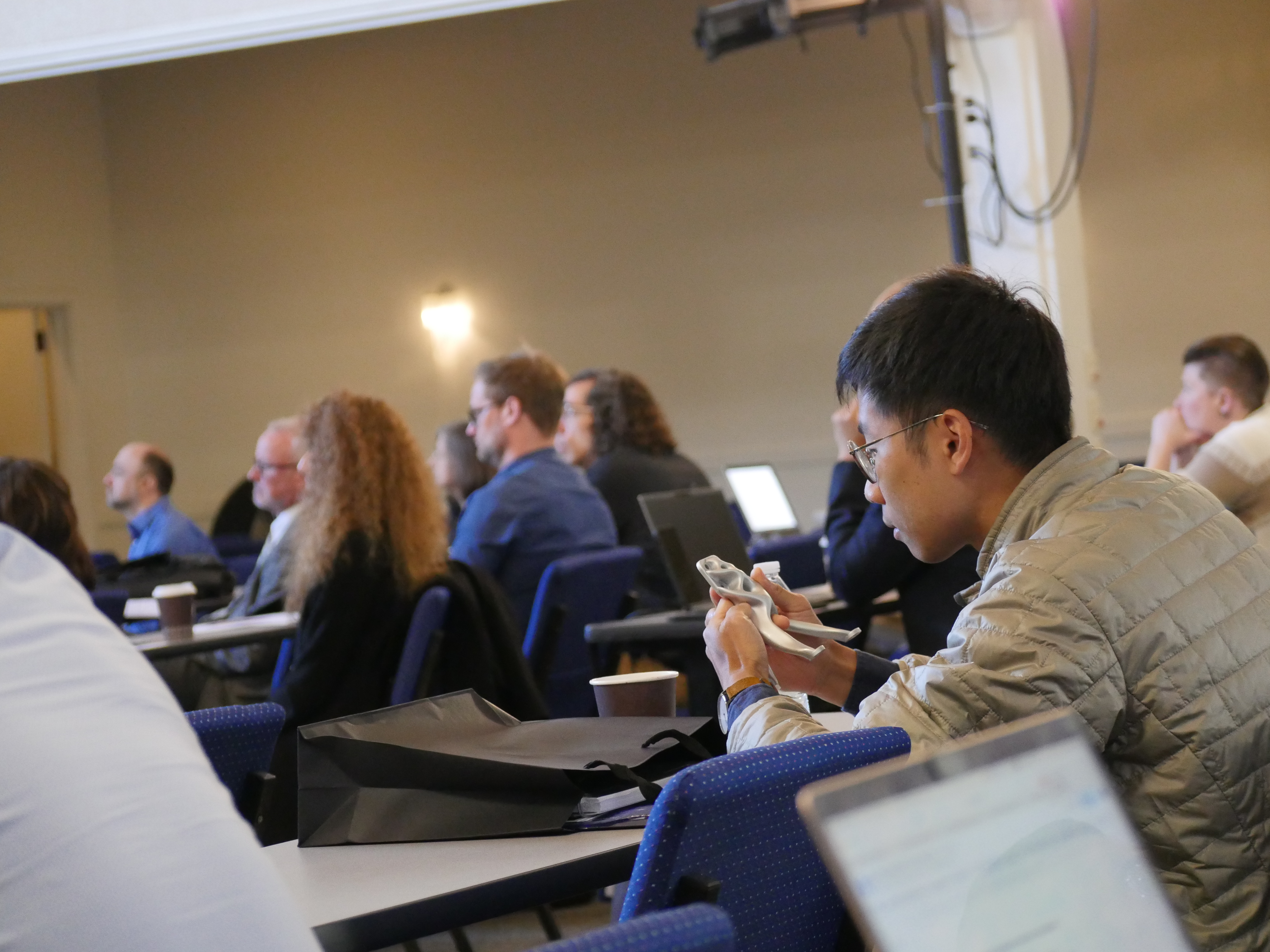 A workshop attendee examines a piece of space hardware made using AI. Photo taken at the 2025 workshop Emerging Technologies for Astrophysics Missi...