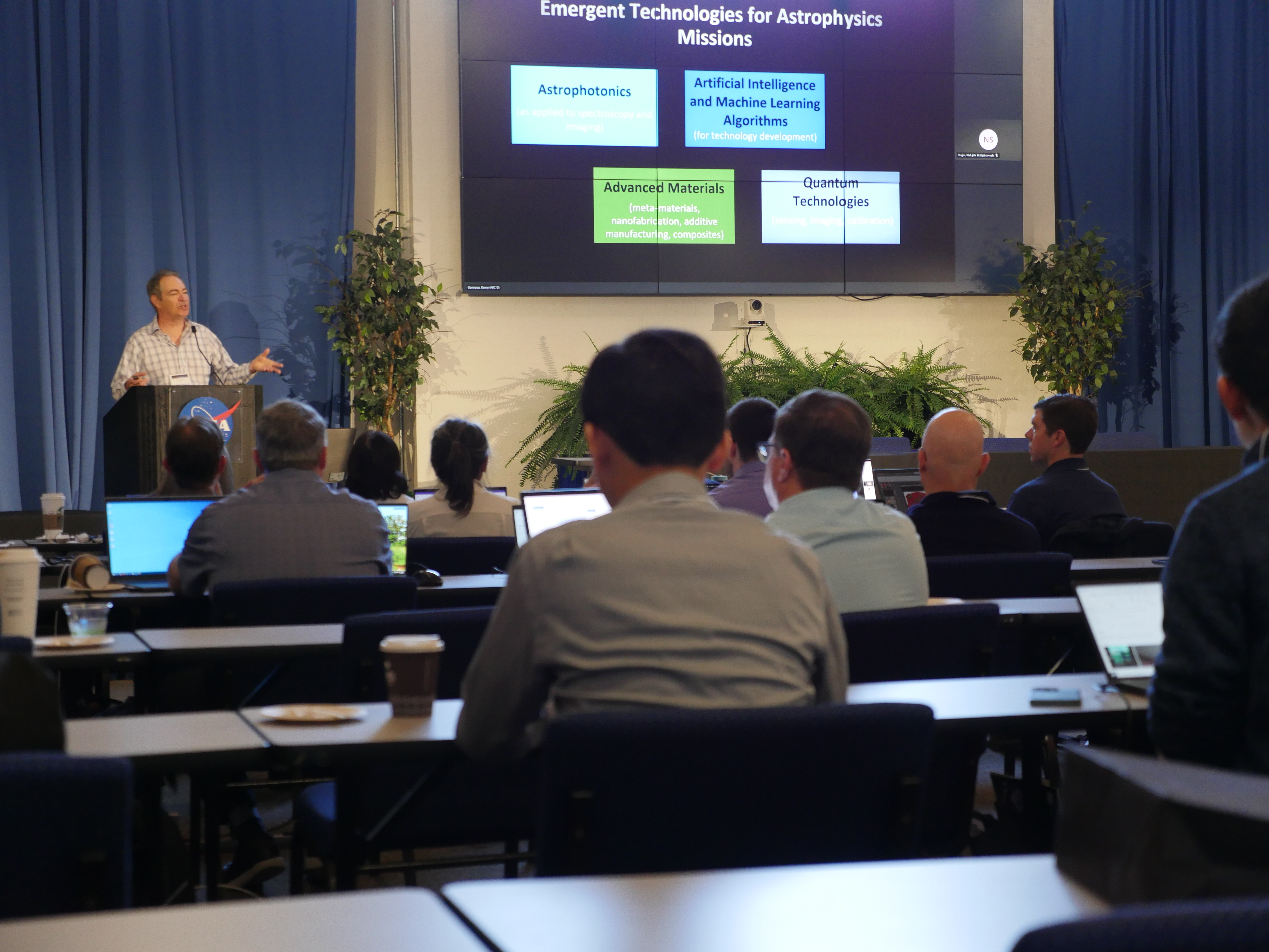 Nick Siegler stands at a podium talking to a crowd of workshop participants. Photo taken at the 2025 workshop Emerging Technologies for Astrophysic...
