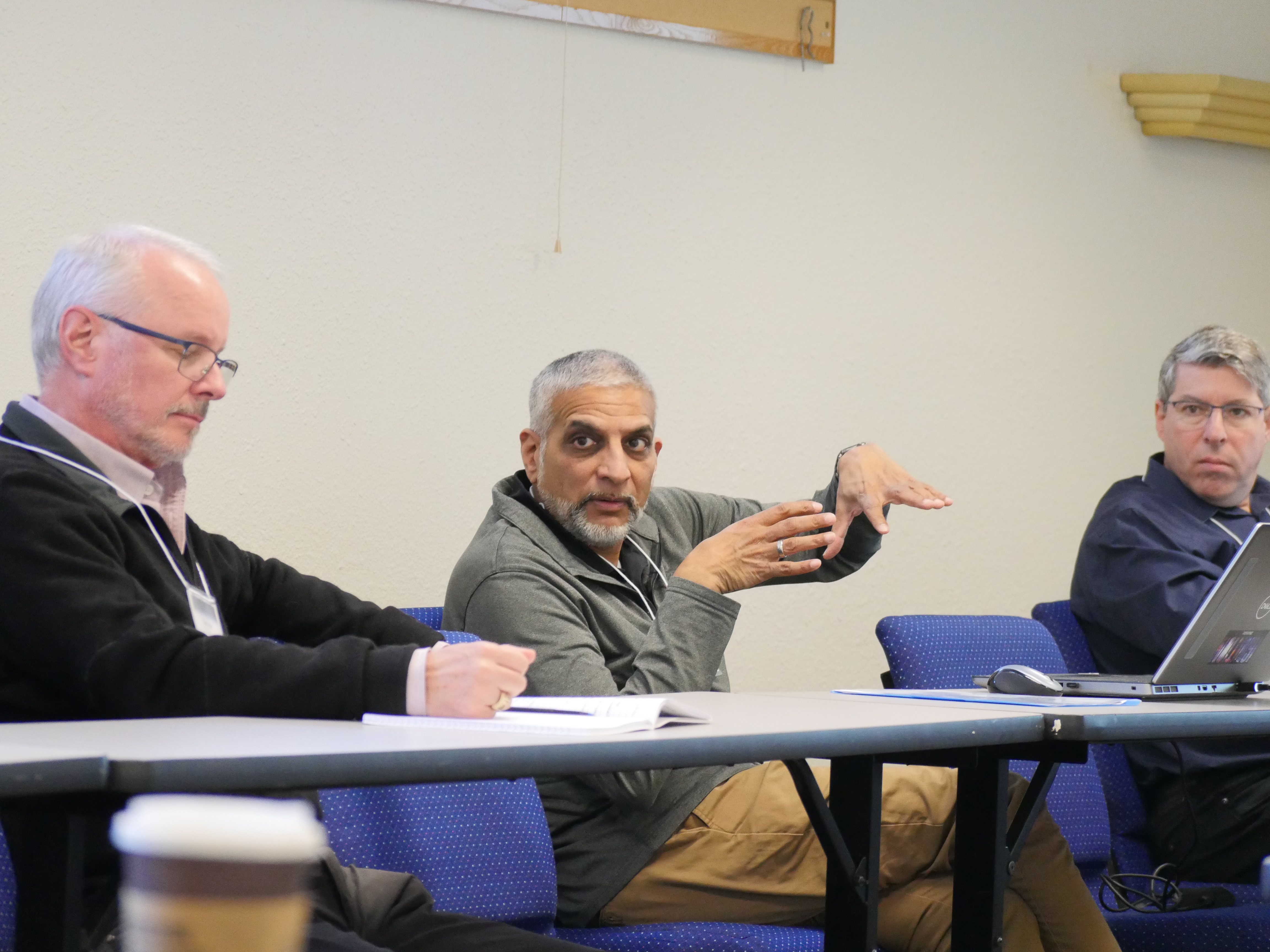 A man sits at a table during a group discussion and discusses his idea. Photo taken at the 2025 workshop Emerging Technologies for Astrophysics Mis...