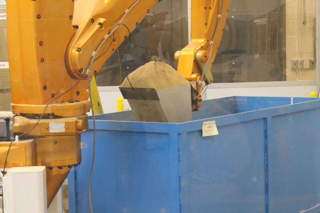 Advanced Planetary Excavator bucket lifted up and filled with GRC-3B at end of dig in soil bin