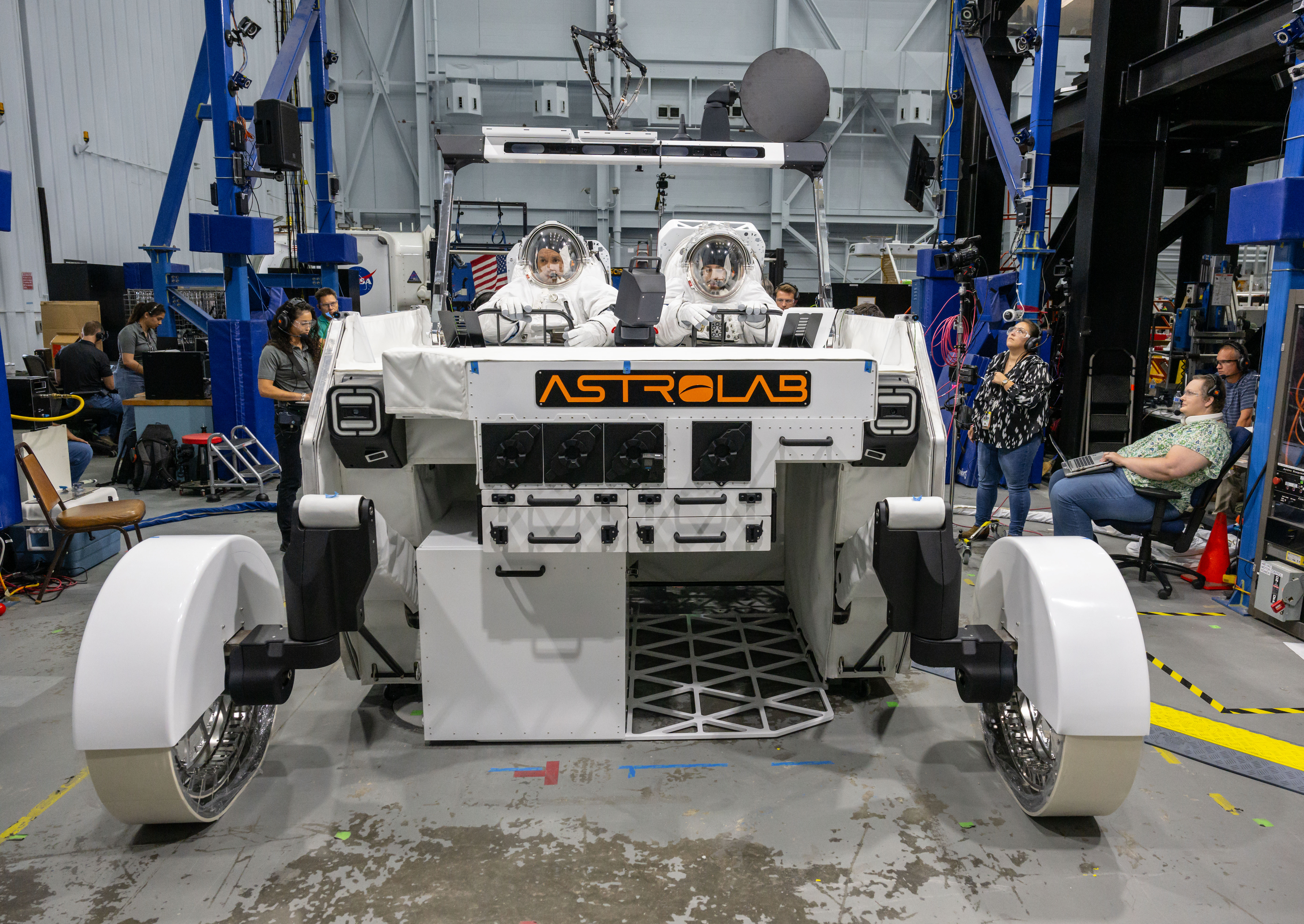 NASA astronaut Frank Rubio and NASA spacesuit engineer Zach Tejral sit inside Astrolab’s FLEX lunar terrain vehicle while wearing white spacesuit...