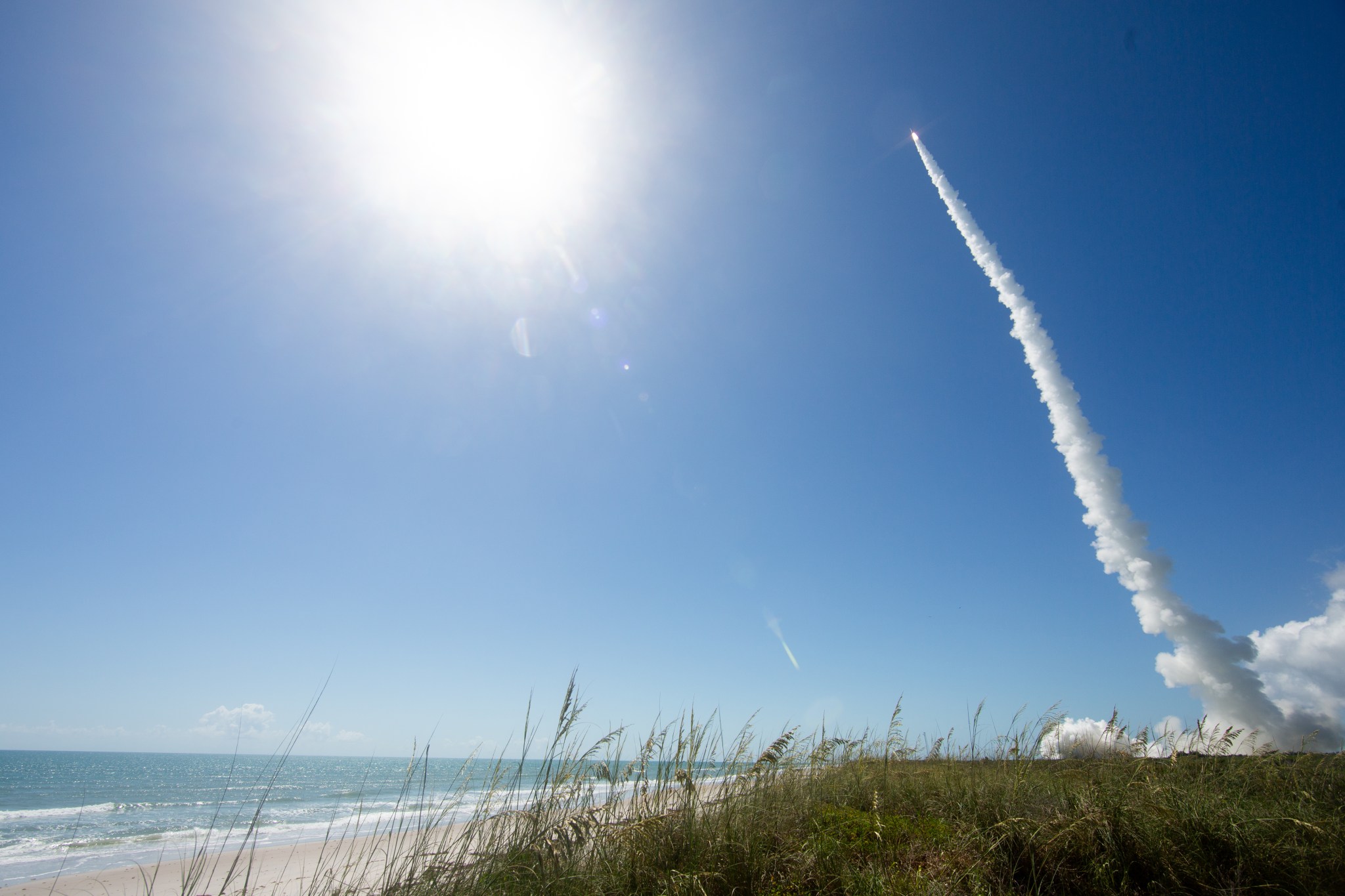 Image shows rocket soaring into the sky with the bright sun in the background at NASA's Kennedy Space Center.