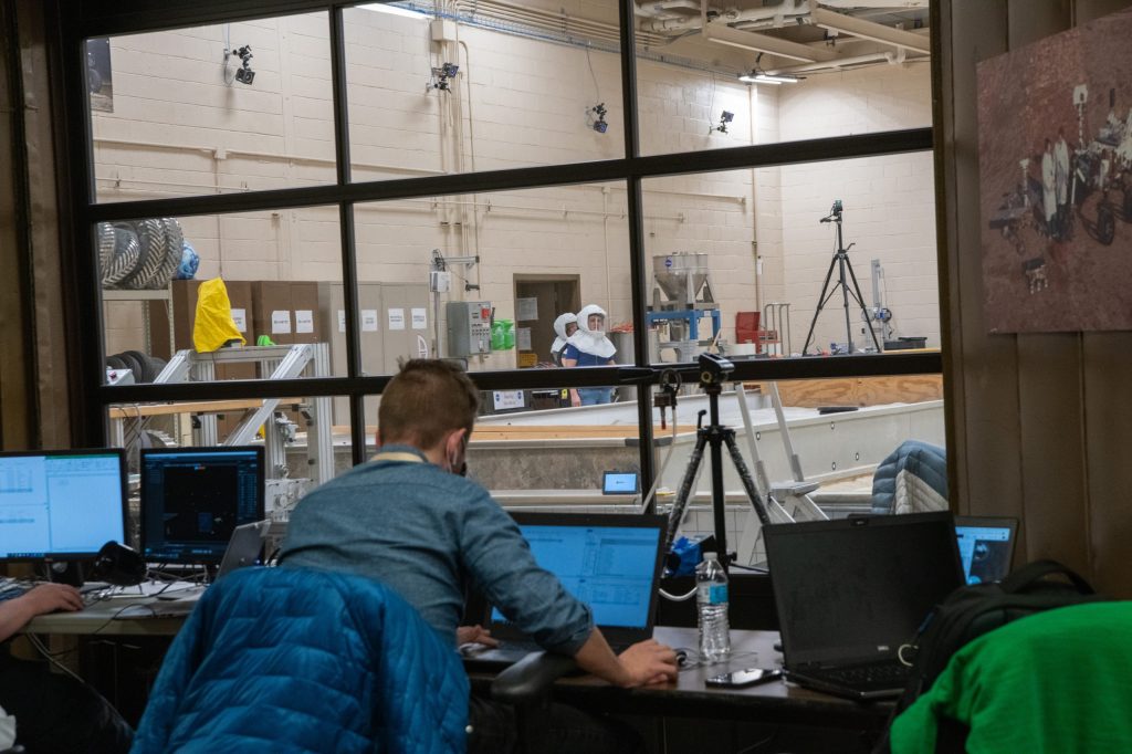 An operator observes rover testing from outside of the Simulated Lunar Operations Laboratory