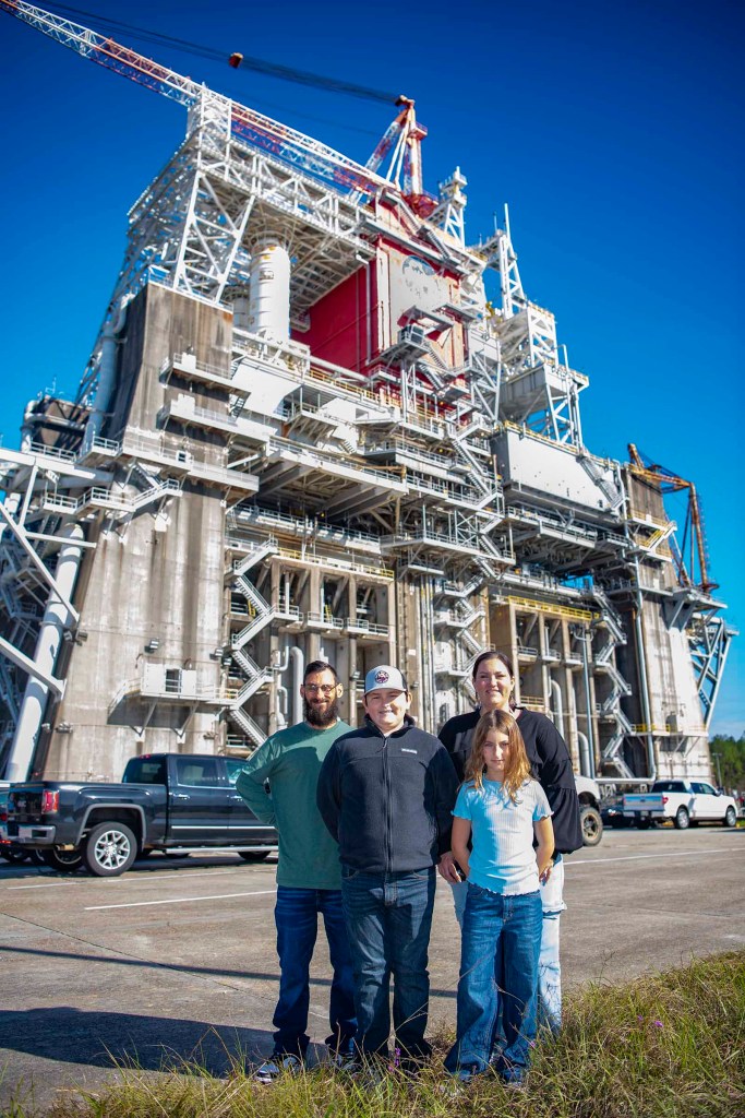 Cookbook author and culinary content creator Caroline Davis, popularly known as Mississippi Kween, and her family pose for a portrait in front of the Thad Cochran Test Stand during their visit to NASA Stennis