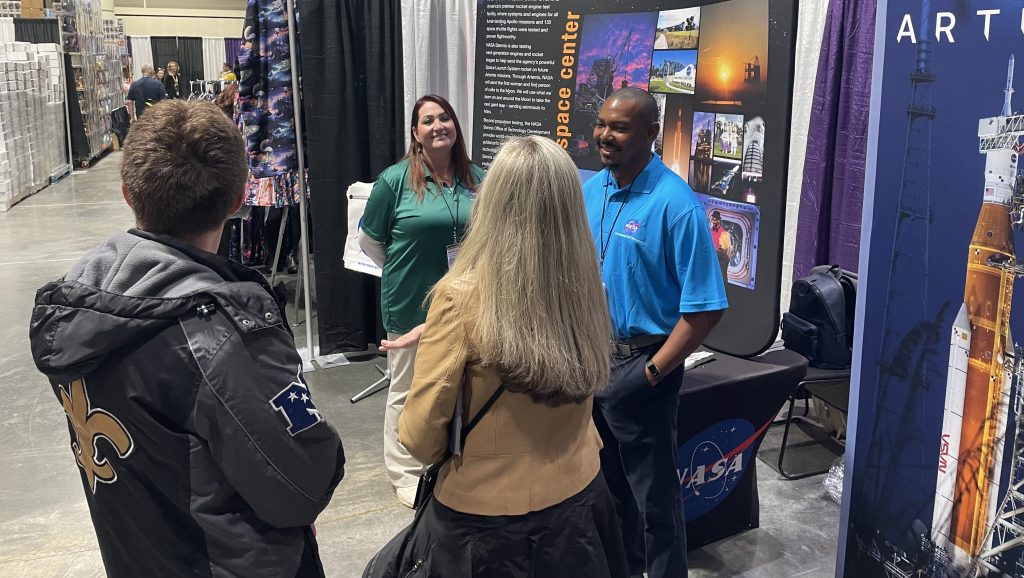 NASA Stennis representatives Patricia White, left, and Robert Smith have a conversation with NASA booth visitors during the 2025 FAN EXPO