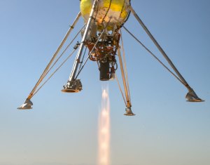 Metal legs of a rocket-powered lander surround a fiery rocket plume in midair. The feet of the lander legs have circular openings for regolith sample collection via PlanetVac.
