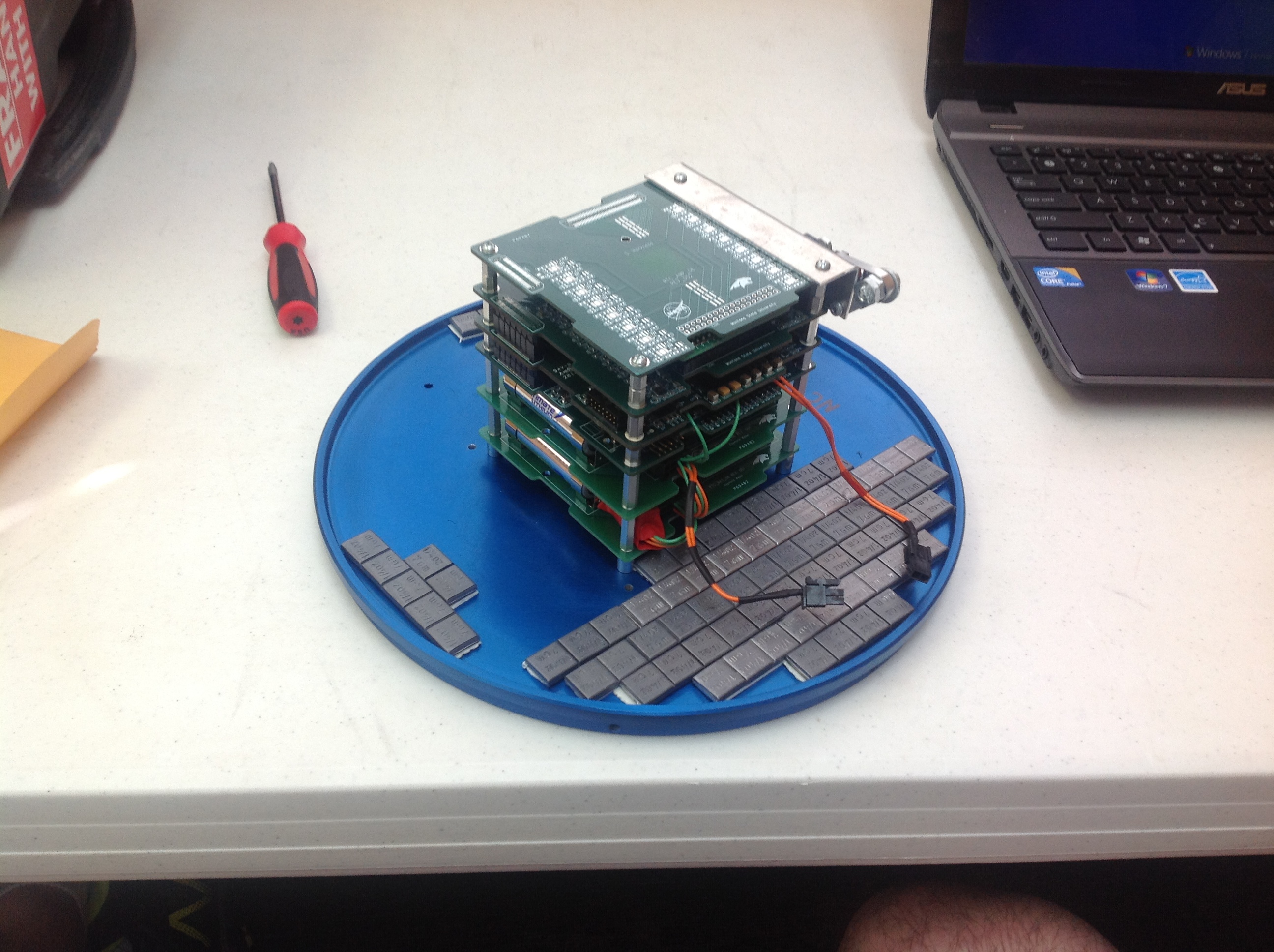 A cube of circuit boards with red wires extending from one side sits on a blue circle.