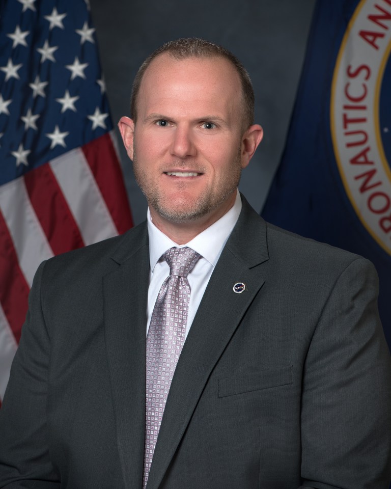 Portrait of Steven Sinacore posing in front of the american flag.