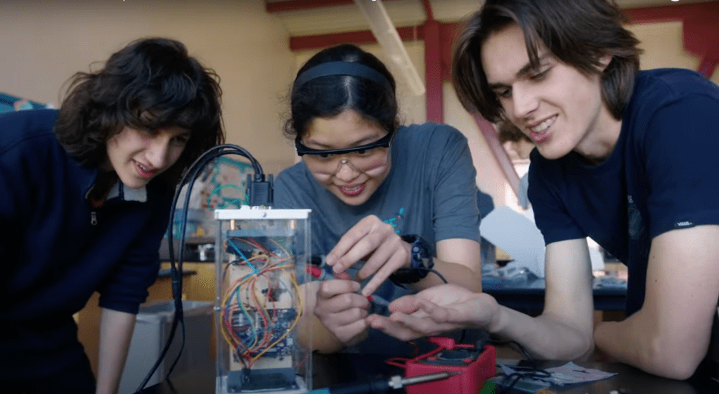 Three high school students work on their experiment.