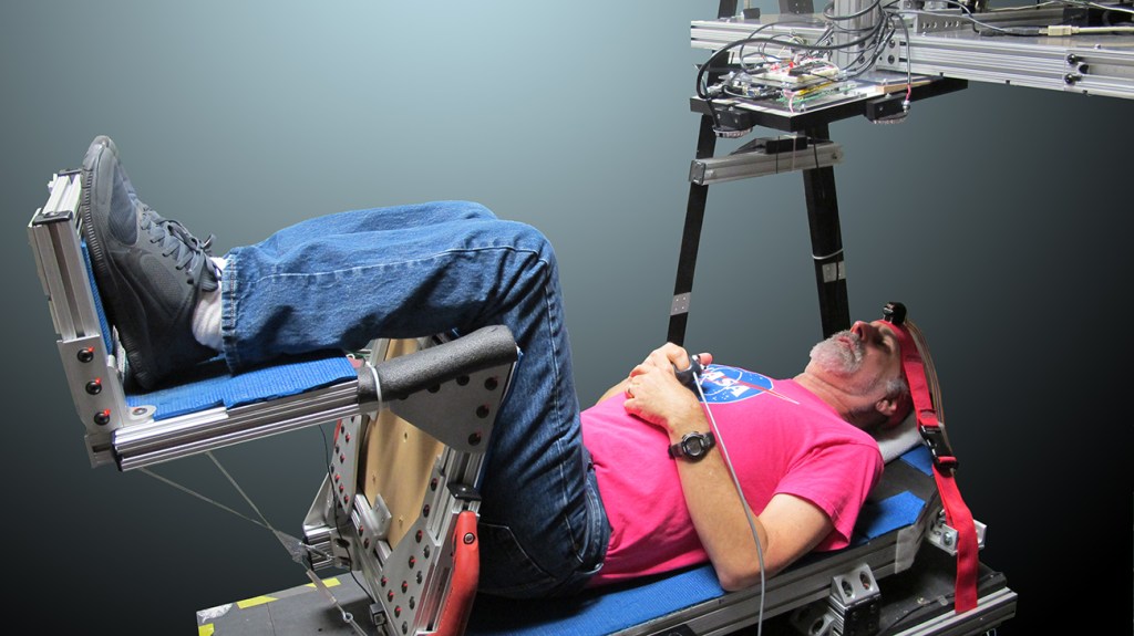 A NASA research subject is sitting in the Human Vibration Laboratory's "Vibration Chair". This chair allows researchers to determine the effects of vibration on visibility and human performance during crew vehicle ascent and entry stages