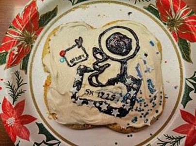 A holiday cookie decorated with an astronaut and cargo bags.