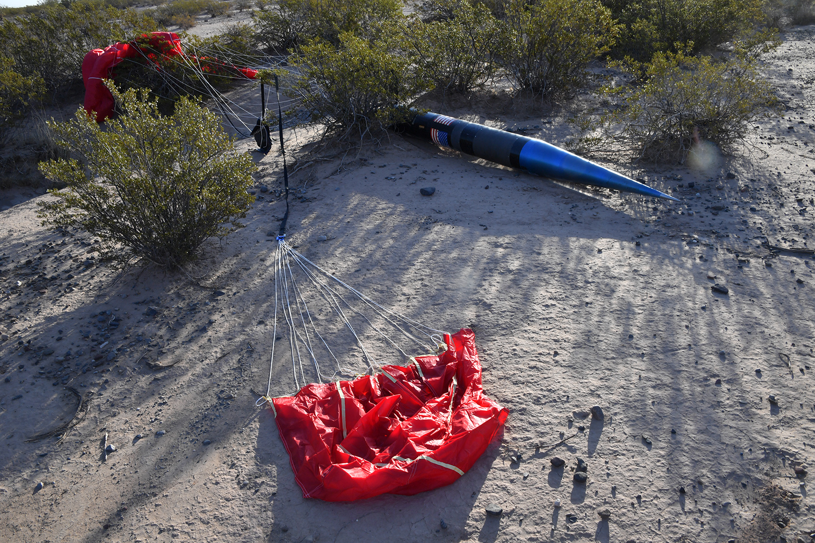 A rocket and red parachute on the ground.