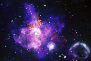 An image of 30 Doradus, or the Tarantula Nebula, looks like a bouquet of purple flowers with orange stamens. Types of data are represented in different colors: X-ray data from NASA’s Chandra X-ray Observatory is blue and green, optical data from NASA’s Hubble Space Telescope is yellow, and radio data from the Atacama Large Millimeter/submillimeter Array is orange. There is a purple and green bubble-like shape at bottom right. This is a superbubble.
