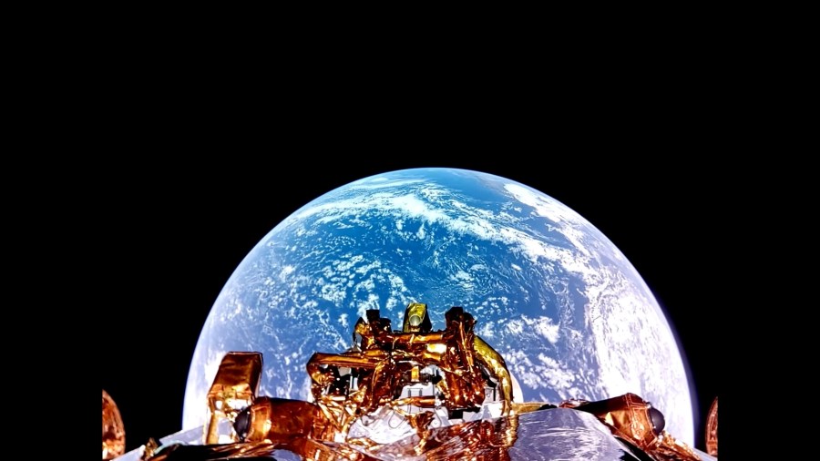 A lunar lander in the center of the image is on its way to the Moon with a bright Earth behind it in the darkness of space.