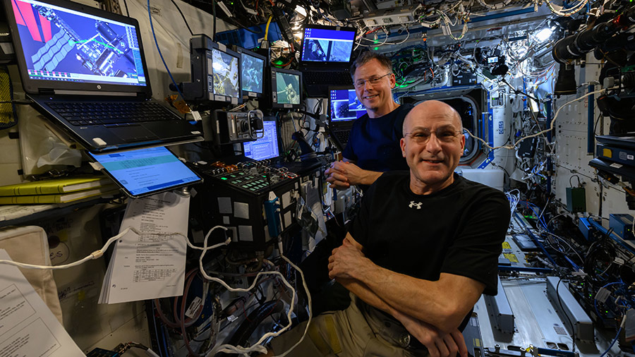 Astronauts Don Pettit (foreground) and Nick Hague are at the controls of the robotics workstation that commands the International Space Station's Canadarm2 robotic arm.