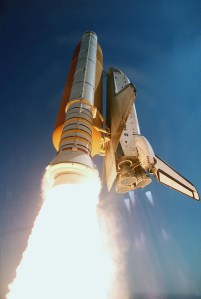 Exhaust from the solid rocket boosters lights up the bottom of this image showing the space shuttle Endeavour launching into space. Blue mach diamonds can be seen to the right of the exhaust, emerging from the main engine nozzles.