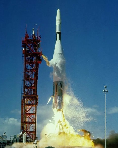 Color image of a rocket lifting off its launch pad, with a blue sky in the background.