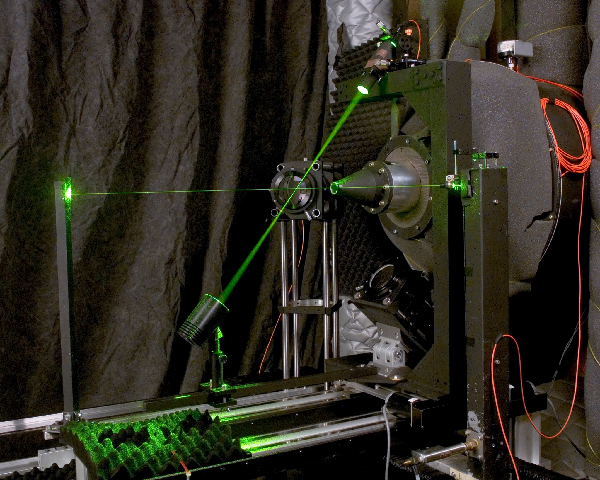 There are two green laser beams propagating through the flow field of a 1-inch diameter round nozzle flow and lens systems to image molecularly scattered light into optical fibers.