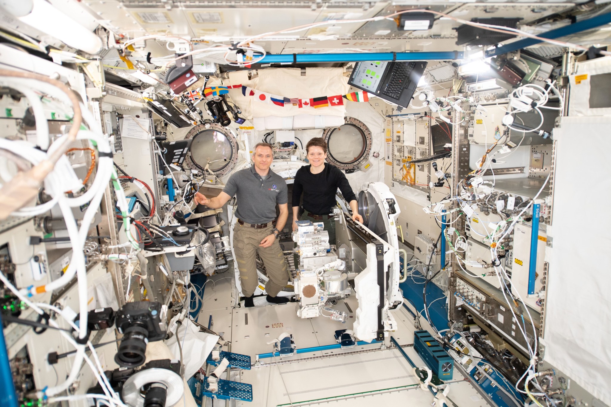 Two astronauts install experimental hardware on the space station.