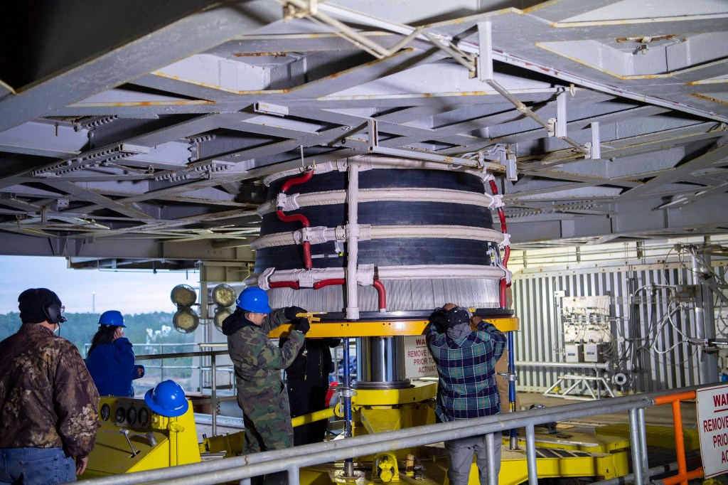crew installing the first new production RS-25 engine on the Fred Haise Test Stand