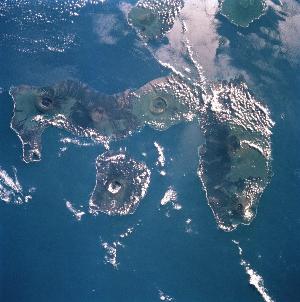 Orbital view of several volcanic islands surrounded by blue water.