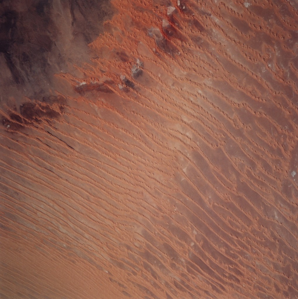Orbital view of a reddish desert landscape.