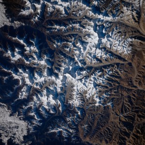 A view of Mount Everest and the surrounding area from space. White snow can be seen on mountains; valleys and shadows appear blue-gray.