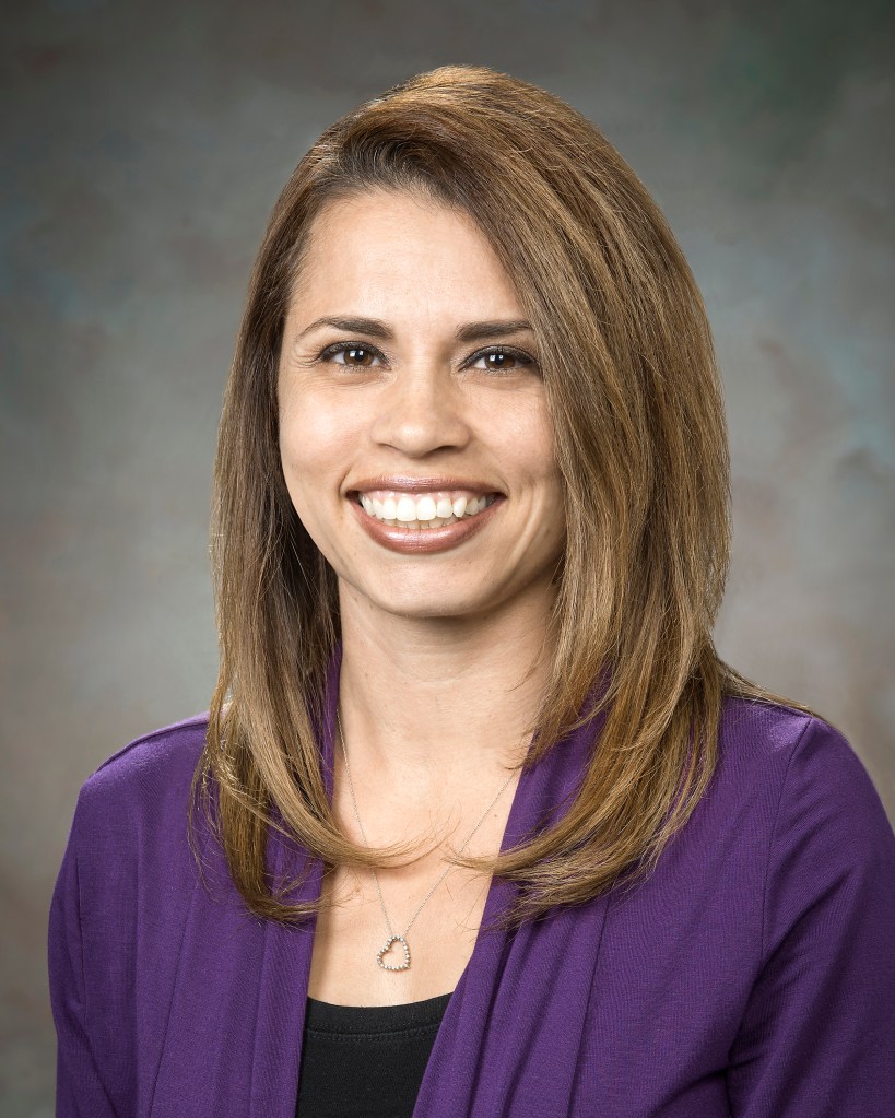 Portrait of a woman wearing a purple and black shirt.