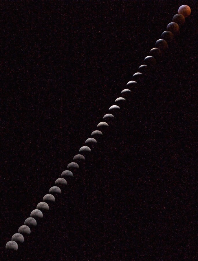 Different phases of the Moon spiral upward against a dark sky in a time-lapsed image during a total lunar eclipse.
