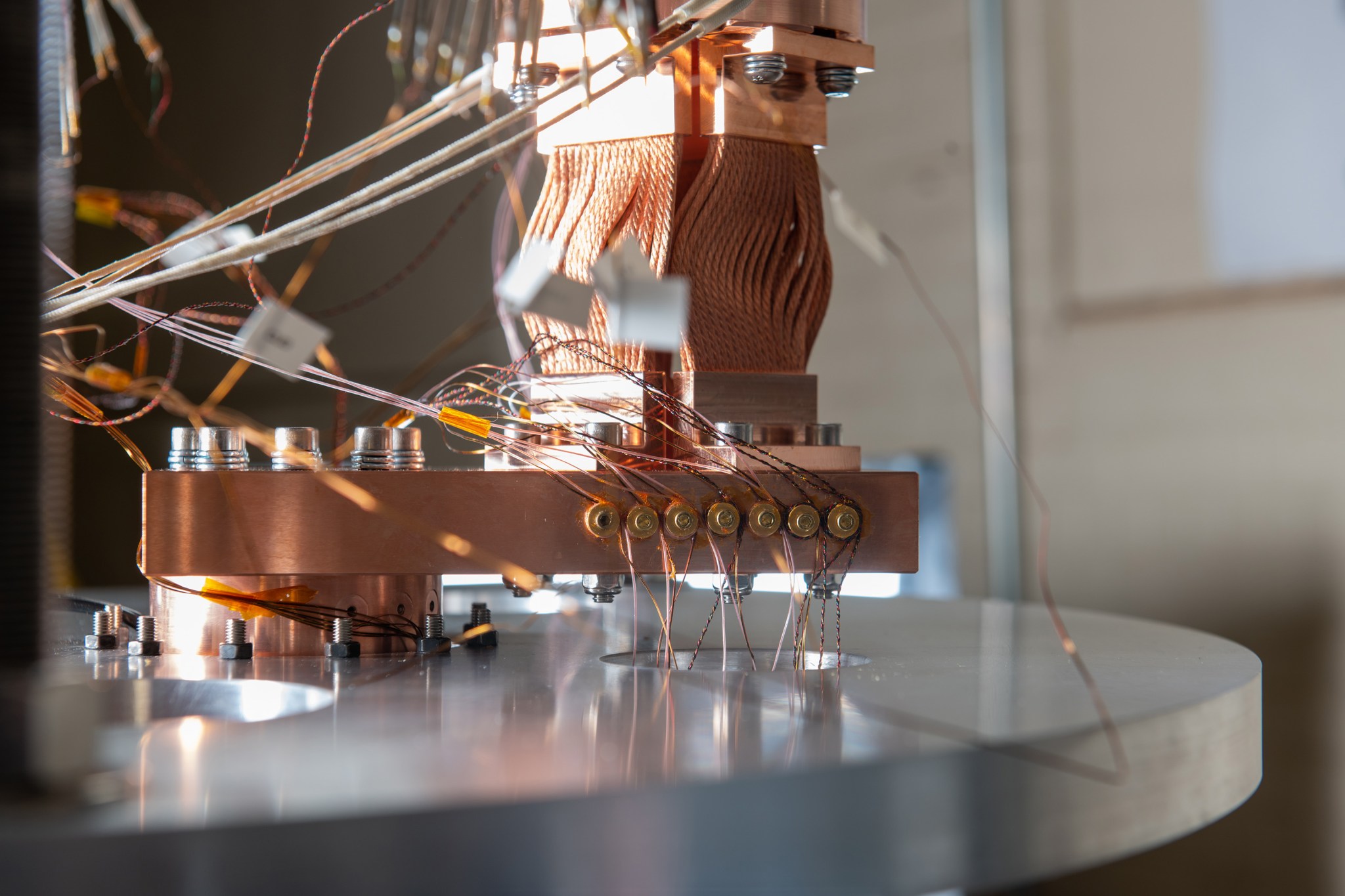 A close-up shot of copper-colored wires bunched together while mounted to a metal testing rig.