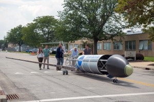 A 25% scale aircraft model with a metal frame structure. The words “SUSAN Electrofan” and “PAX 180” are printed on a graphic along with fuselage, with a large NASA insignia in the center of the plane. The rear of the aircraft model, along with the wings and tail, are taken apart to display the inner components that make up its electrified propulsion system.