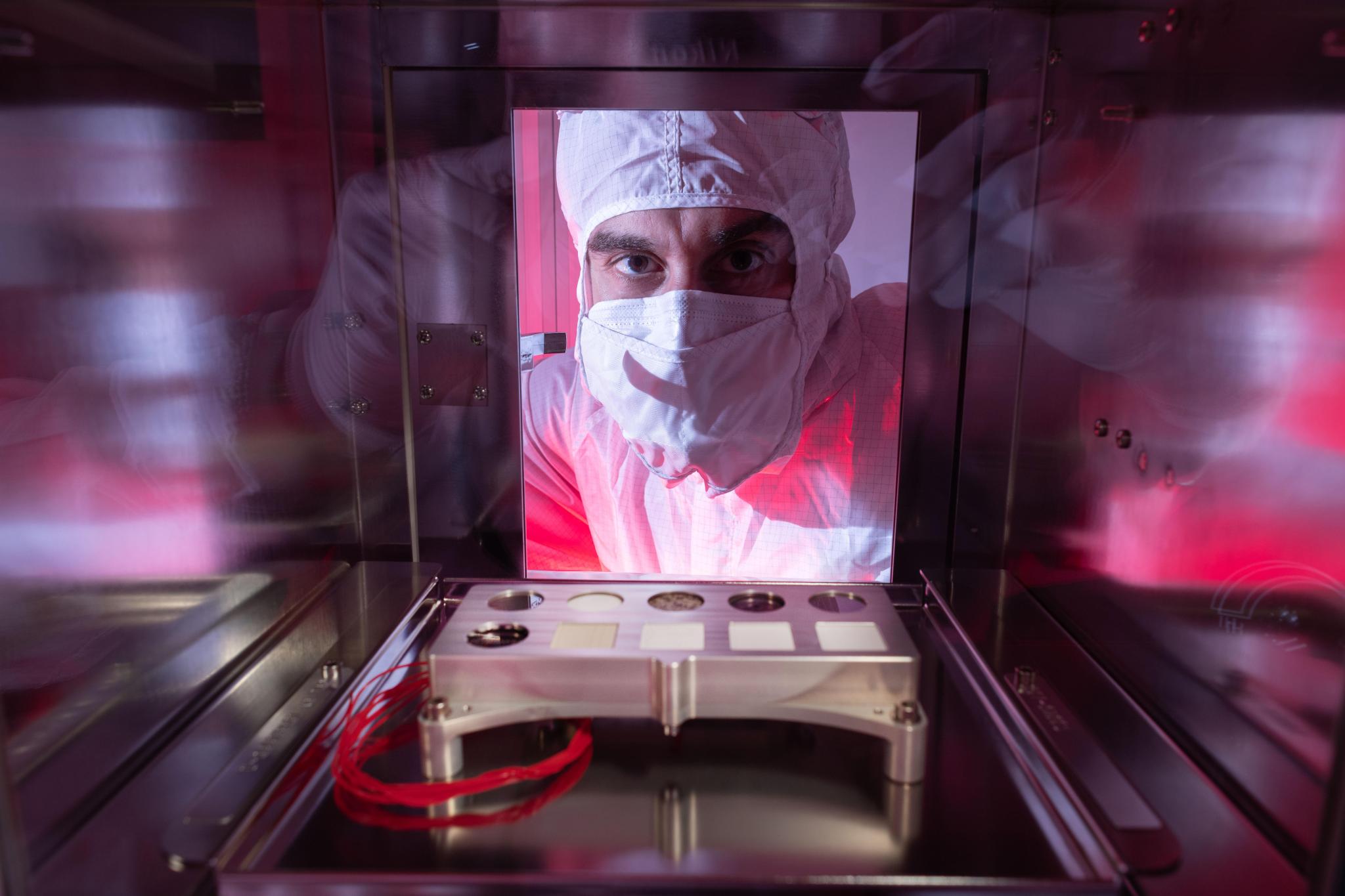 NASA scientist Trevor Graff peers at a calibration target designed to help fine-tune settings on the Scanning Habitable Environments with Raman & Luminescence for Organics and Chemicals (SHERLOC) instrument carried aboard NASA's Perseverance Mars rover.