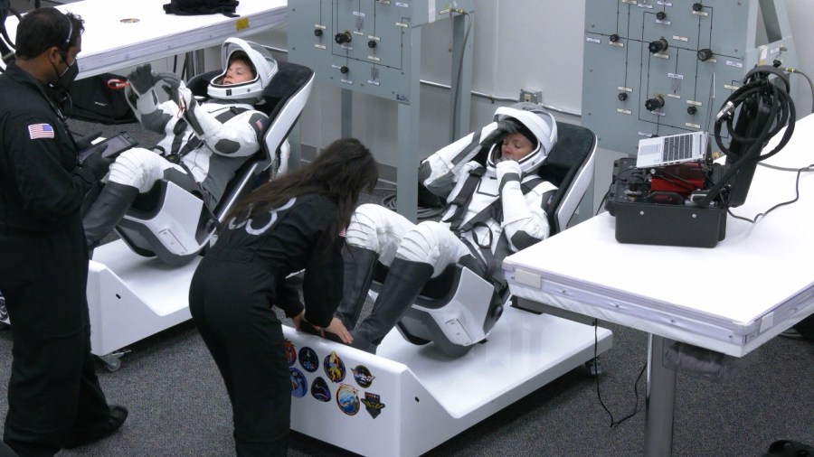Image shows two astronauts in their space suits.
