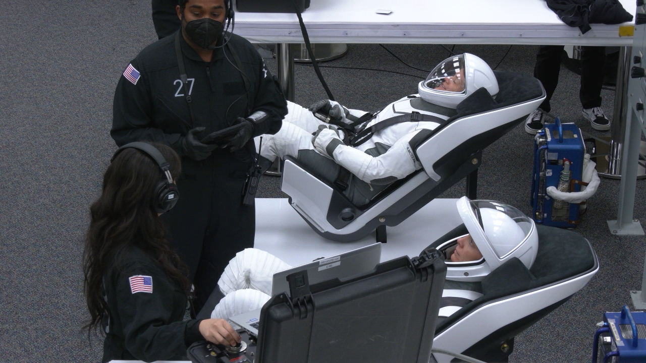 Image shows astronauts suiting up in spacesuits.