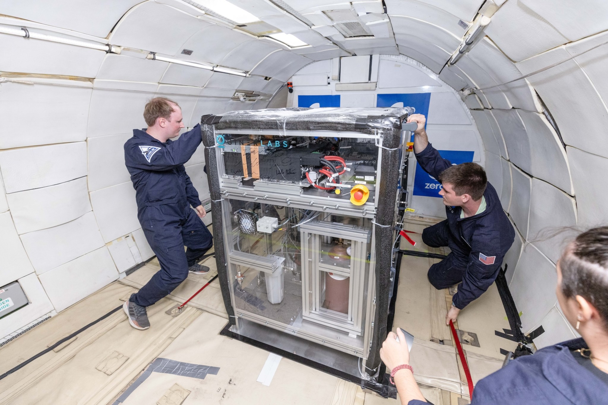 Two researchers on a parabolic flight monitor their experiment in zero gravity.