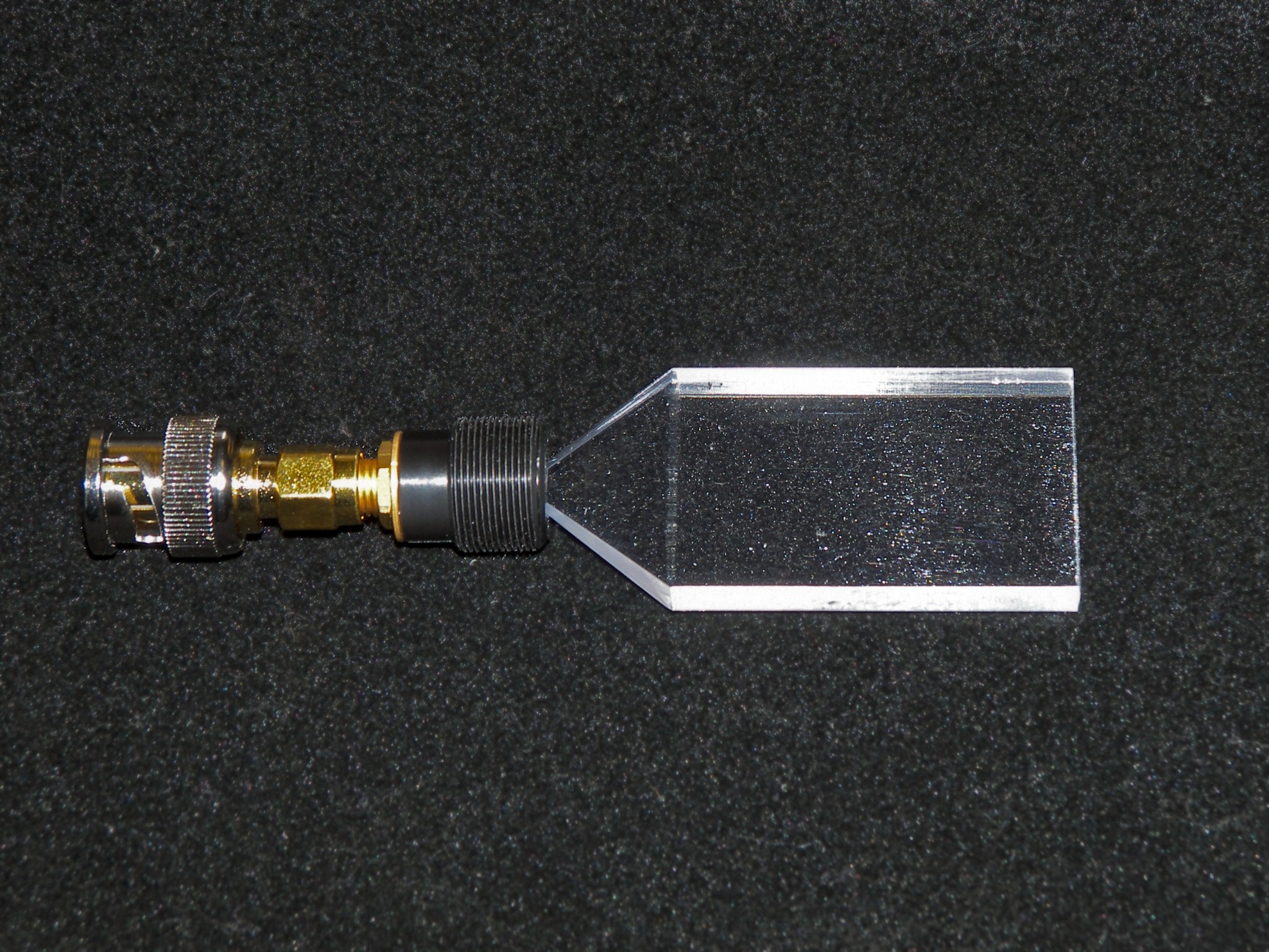 Photograph of a plastic scintillator block attached to a small detector set against a black background.