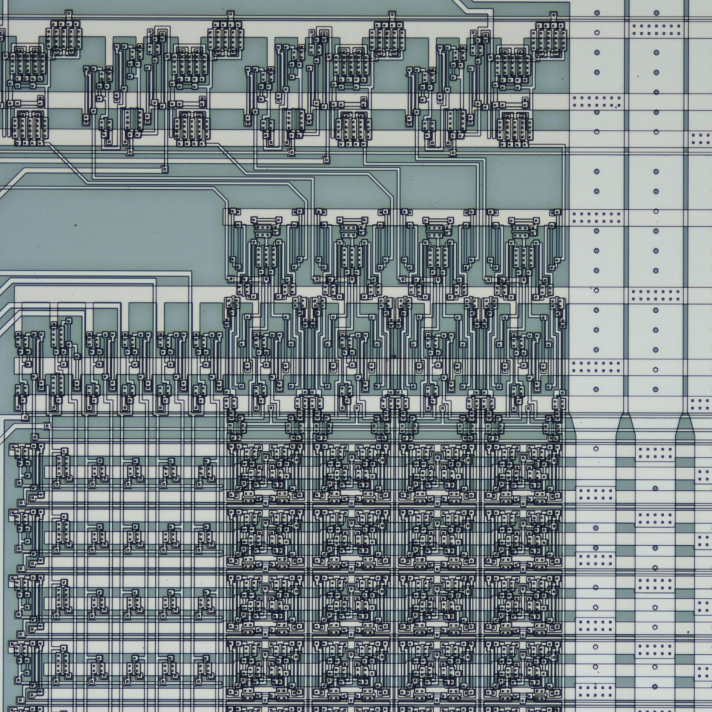 Close-up view of a silicon carbide random access memory microchip showing an overhead microscopic view of a complex network of metal lines interconnecting numerous small silicon carbide transistors forming the memory integrated circuit .