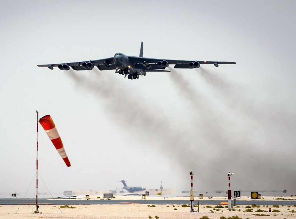 Bomber taking off with heavy exhaust trails.