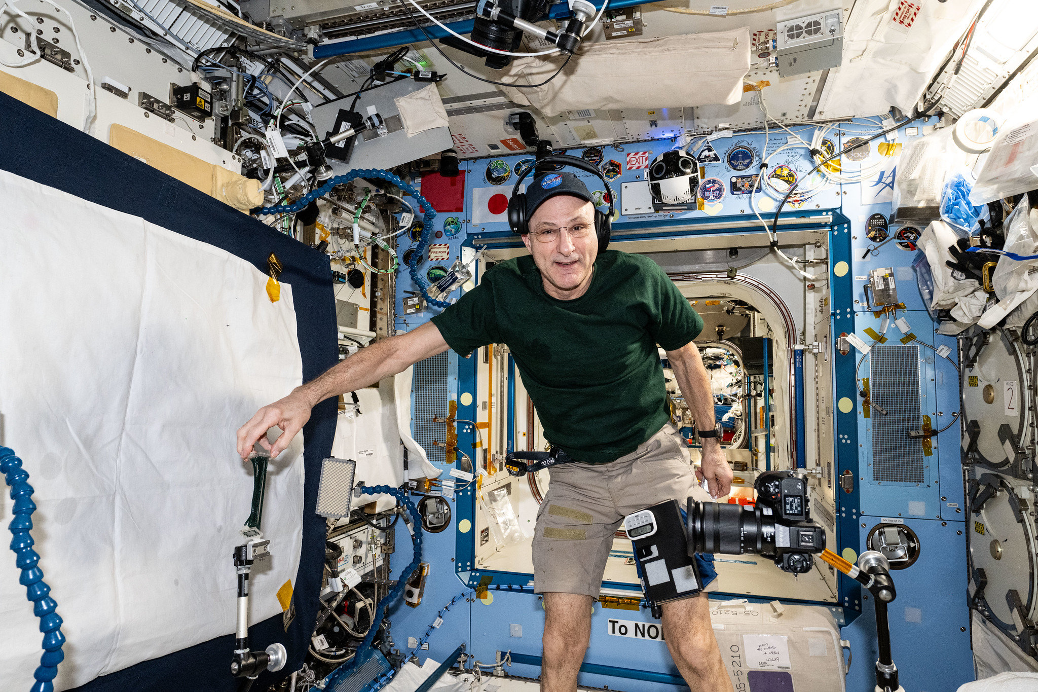 An image of NASA astronaut and Expedition 72 Flight Engineer Don Pettit setting up camera hardware in the International Space Station.