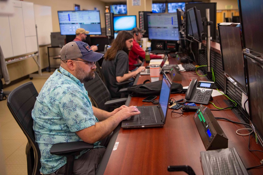 several members of the engineering and operations team are shown seated and reviewing data